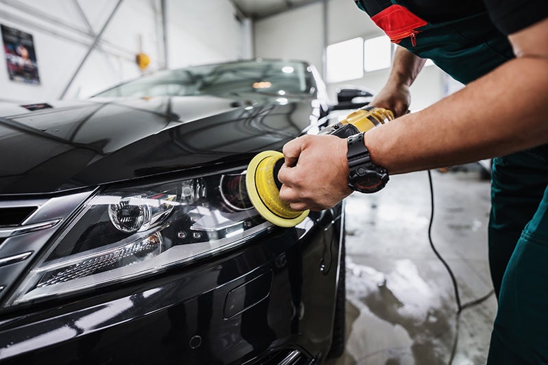 Bodyshop worker working on car headlight